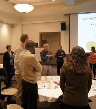 A group of people standing in a room together and one person is talking.