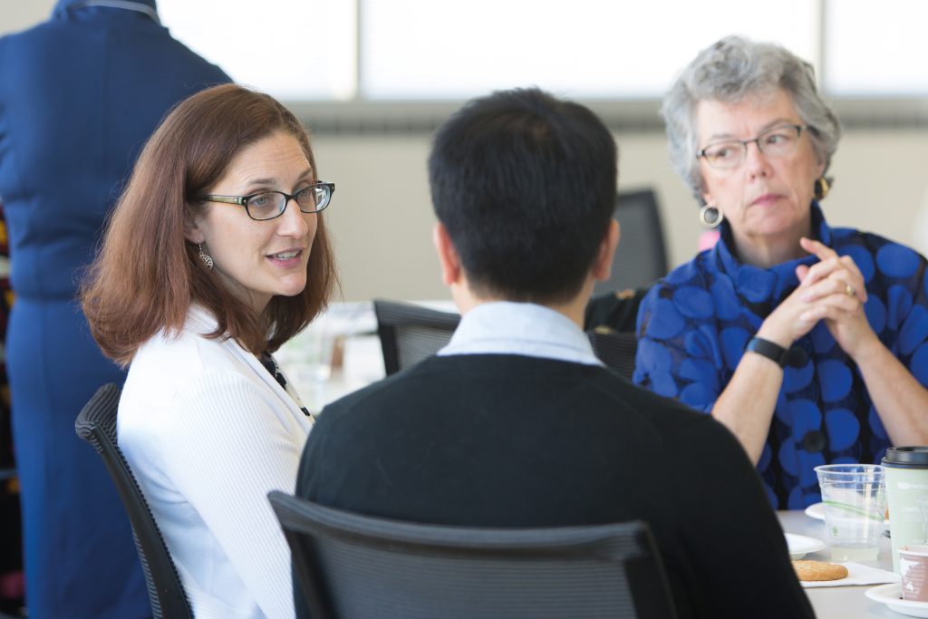 A group of three people having a discussion at a table.